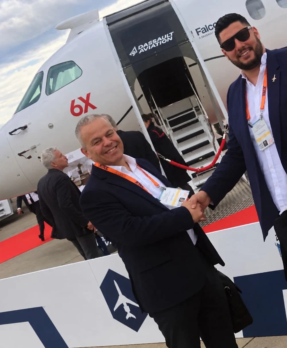 Laurent Travostino shaking hands with a contact in front of a Dassault Falcon 6X at an air show